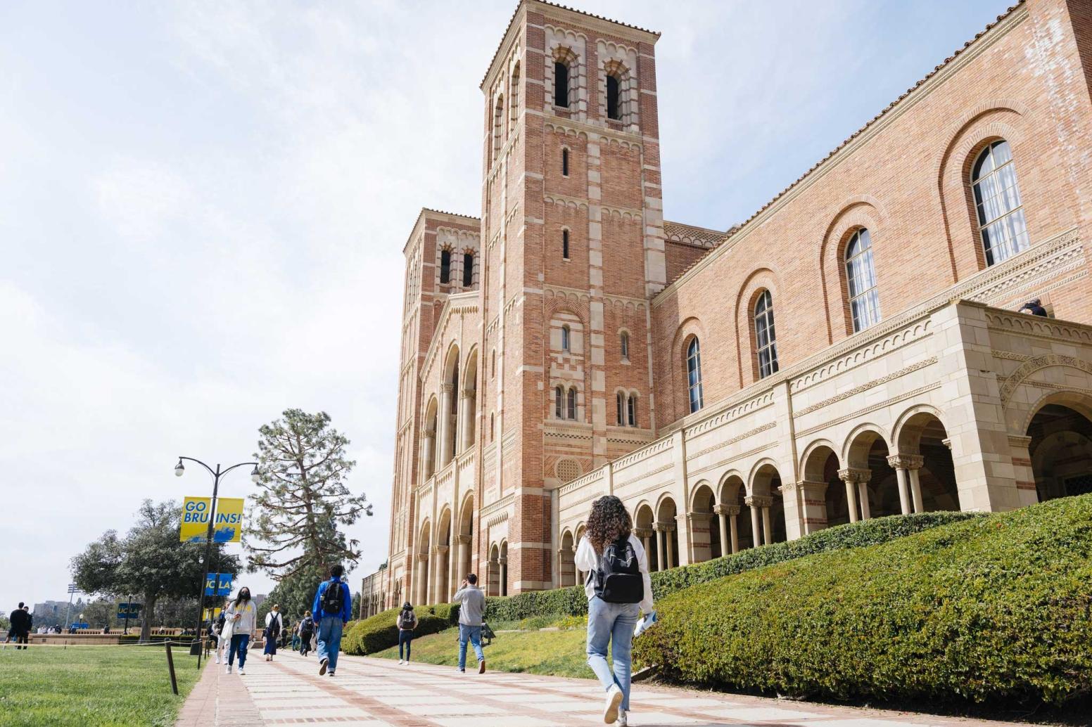campus residents stroll by the towers of Royce Hall