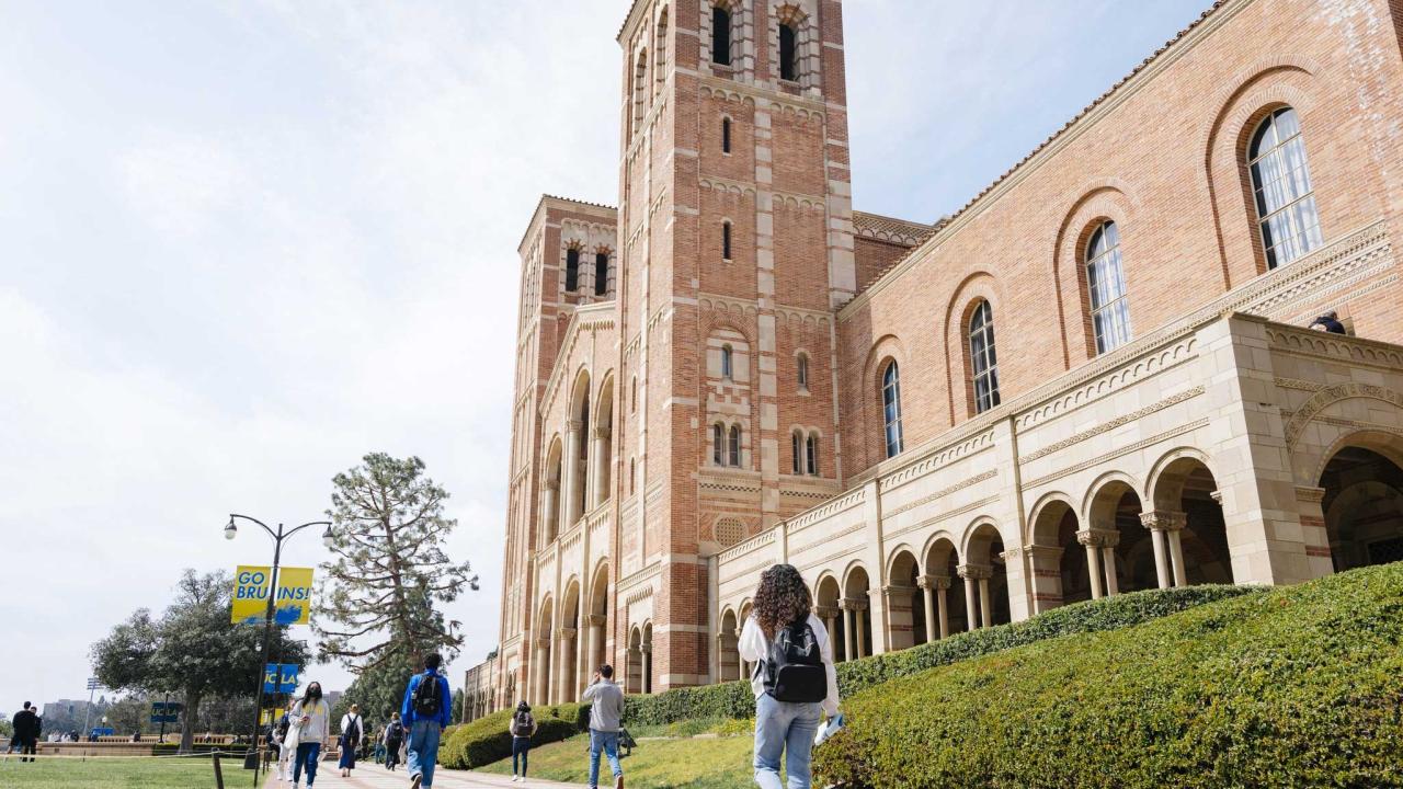 campus residents stroll by the towers of Royce Hall