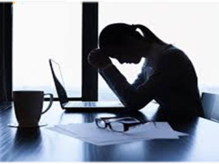 woman in shadow bending head over computer